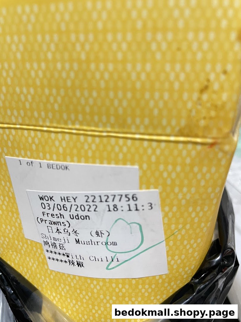 Yellow food container with an order label for udon and mushrooms.