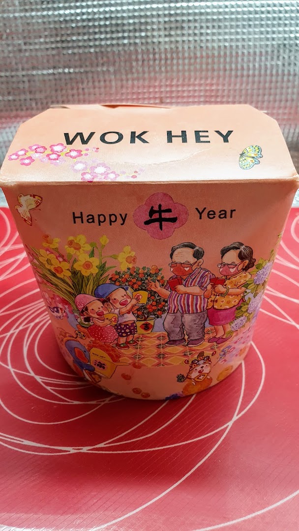 Close-up of a WOK HEY food container with a festive 'Happy 牛 Year' design.