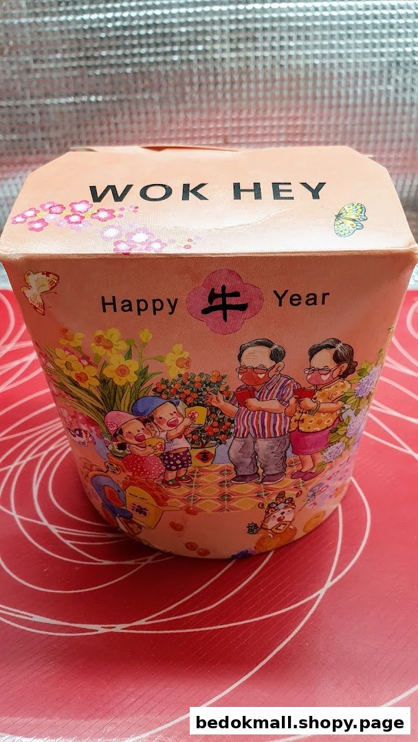 Close-up of a WOK HEY food container with a festive 'Happy 牛 Year' design.