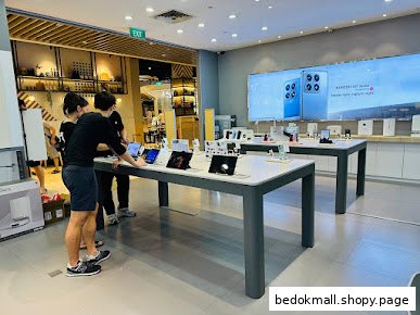 Customers interact with electronic devices on display in a retail store.