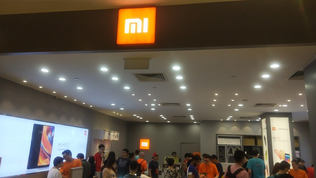 Interior view of a busy Xiaomi store with customers and product displays.