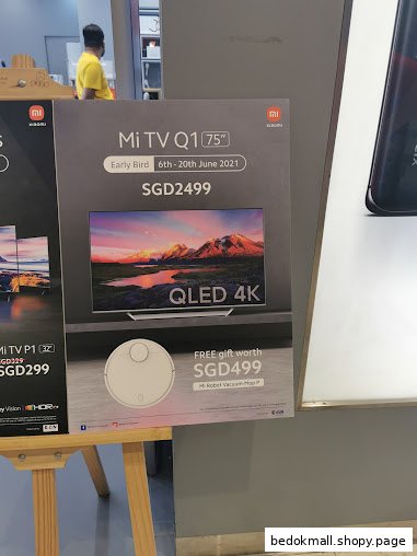 Large sign advertising Xiaomi TVs and robot vacuum with prices and promotions.