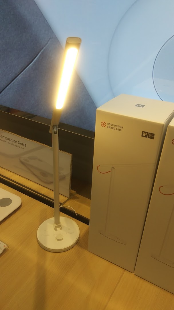 A lit desk lamp and its product box displayed on a wooden surface in a shop.