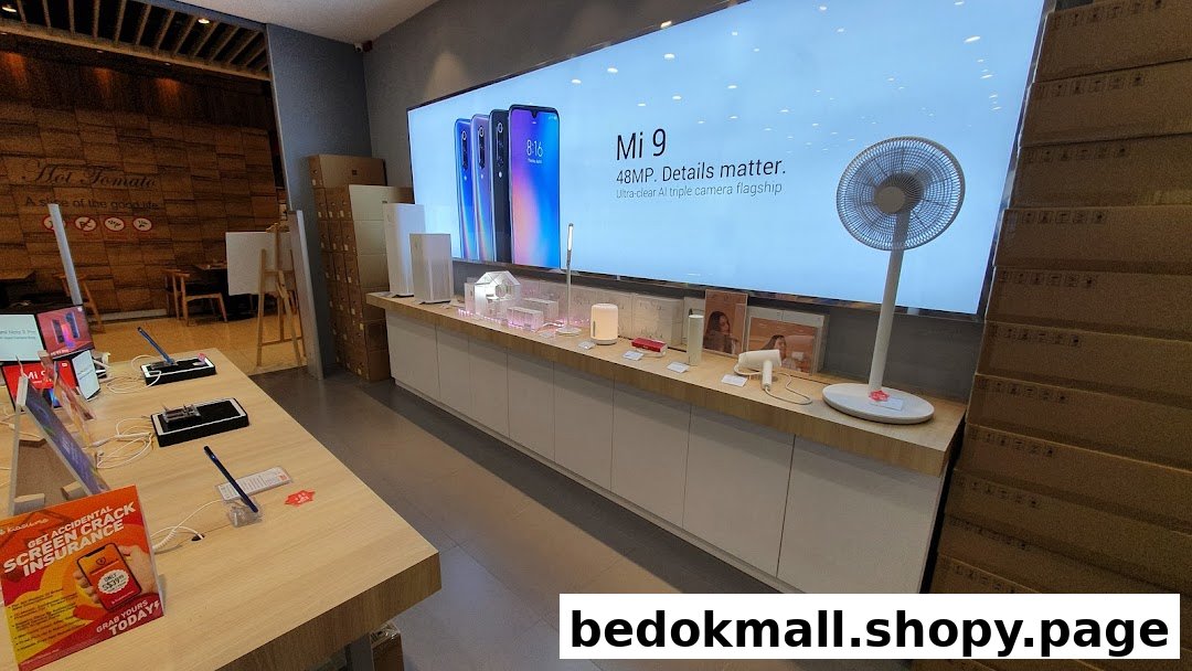 Interior of a Xiaomi store showing phones, electronics, and a large product display screen.