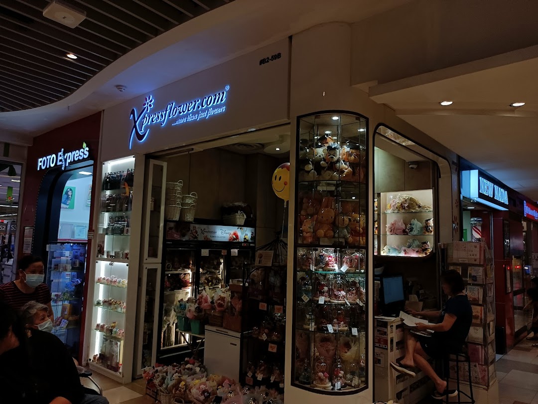 Front view of Xpressflower shop with product displays and a person inside.