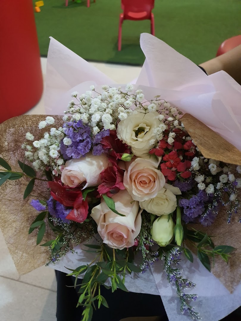 A colorful bouquet of roses and other flowers wrapped in paper.