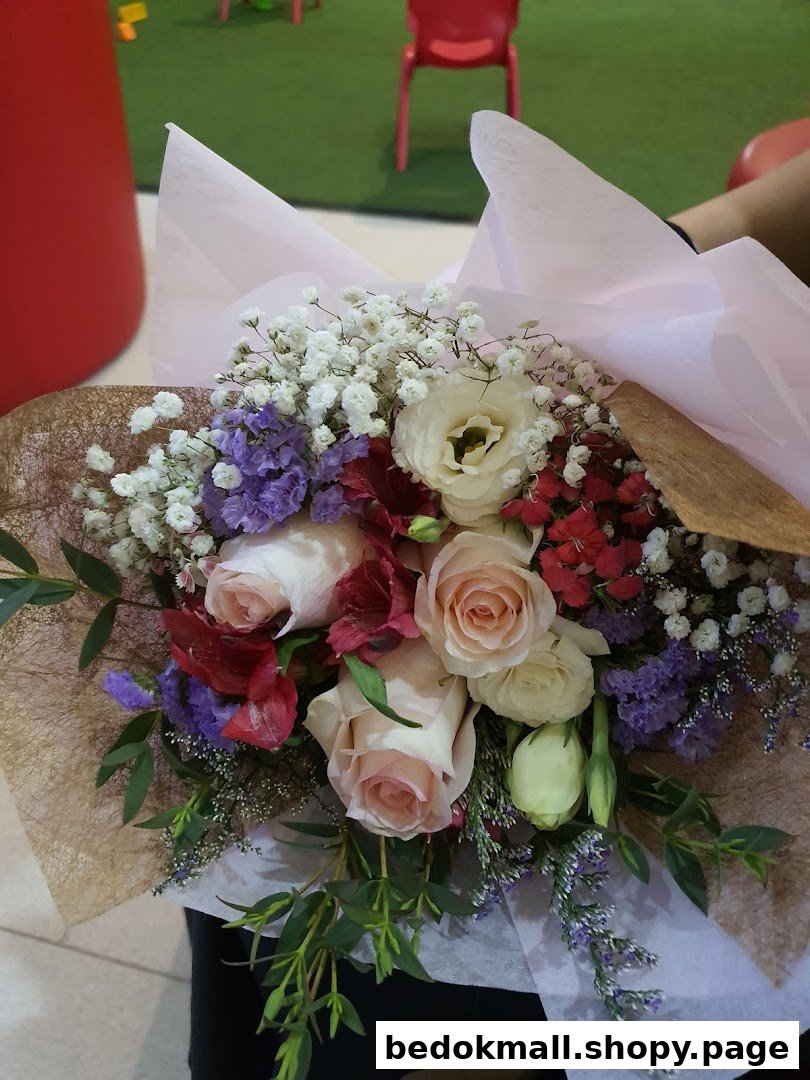 A colorful bouquet of roses and other flowers wrapped in paper.