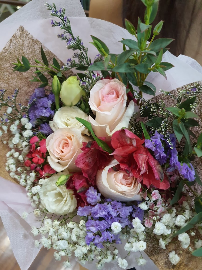A vibrant bouquet featuring pink and white roses, baby's breath, and purple flowers.