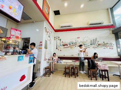Interior view of a cafe with a counter, customers, and a wall mural.