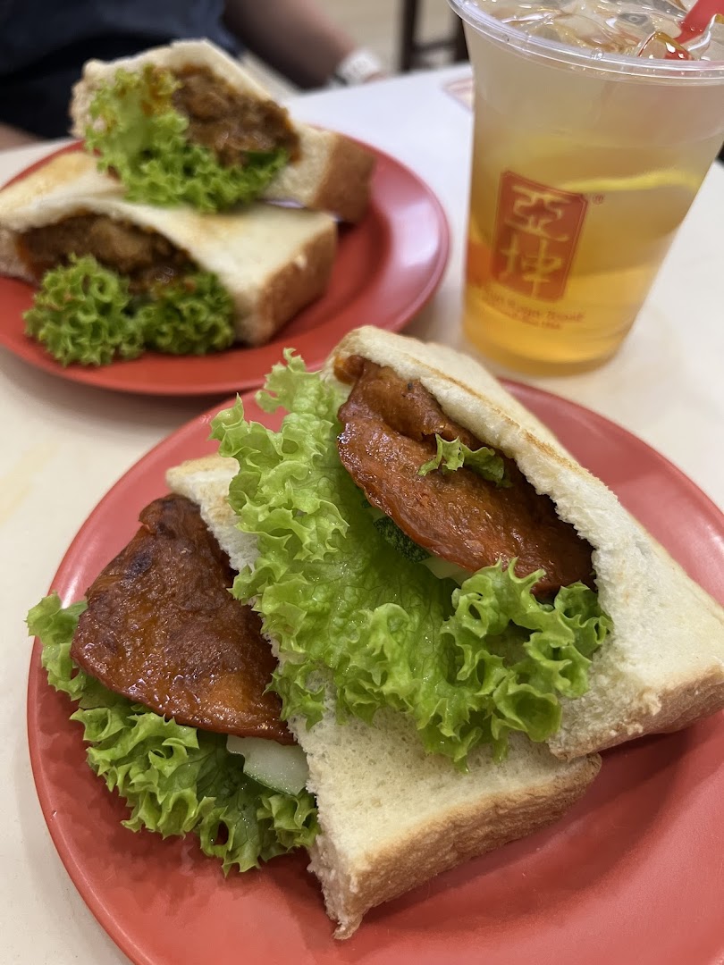 Two sandwiches with lettuce and meat, and a drink on a table.