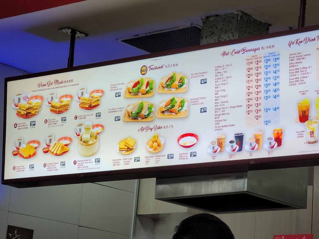 An illuminated menu board displaying food and drink items with prices.