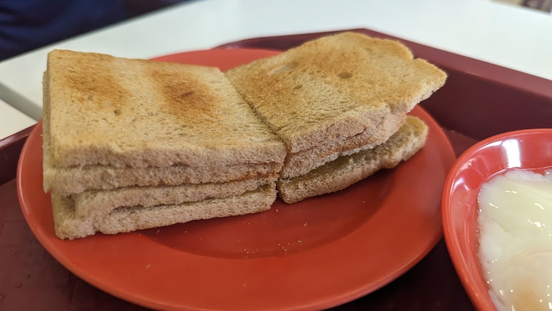 Toasted bread slices and a bowl of soft-boiled eggs on a red tray.