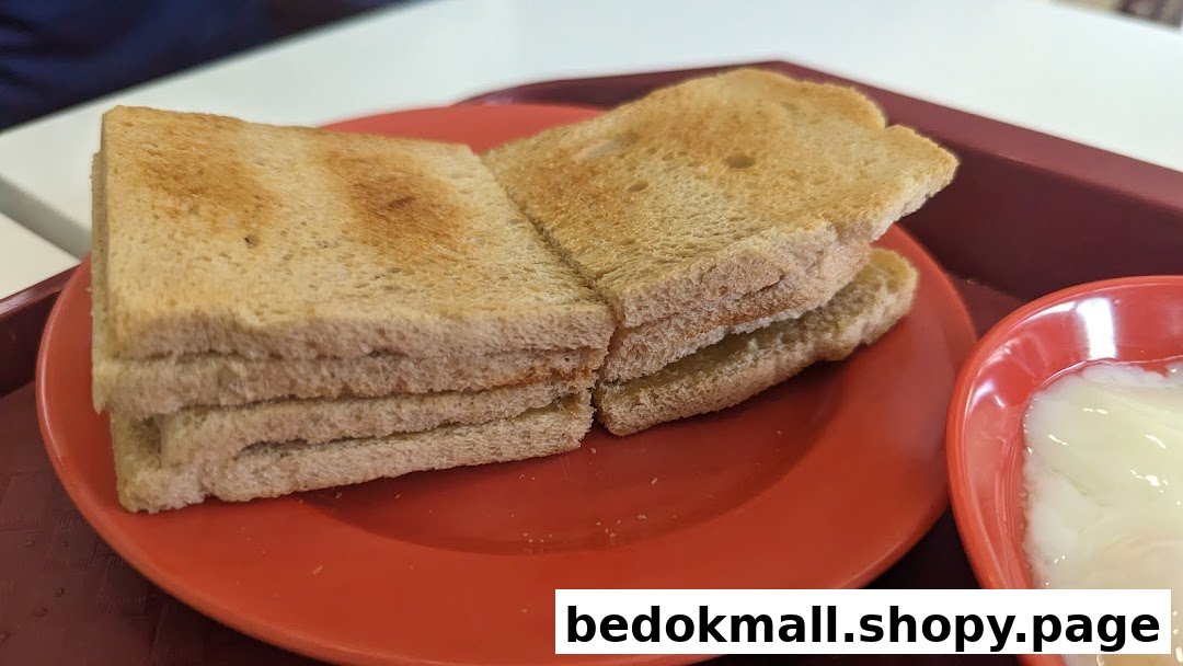 Toasted bread slices and a bowl of soft-boiled eggs on a red tray.