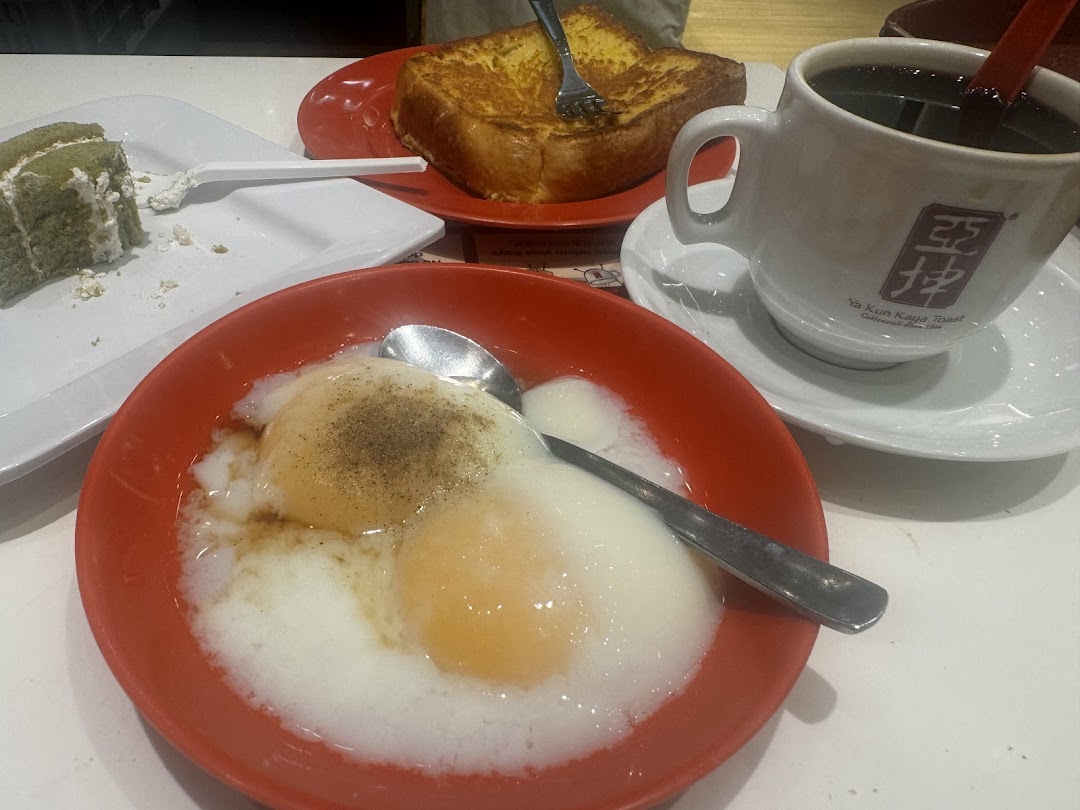 A table with soft-boiled eggs, French toast, cake, and coffee from Ya Kun Kaya Toast.