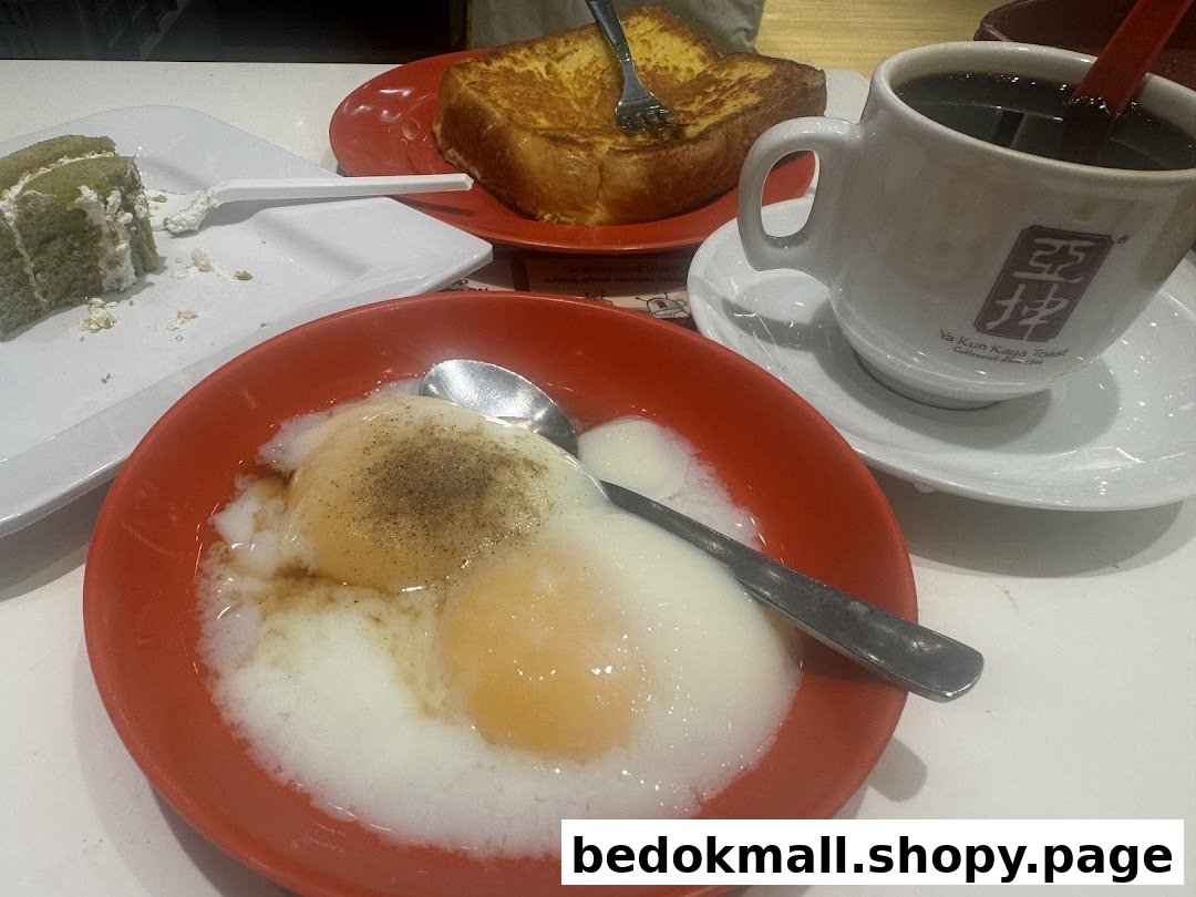A table with soft-boiled eggs, French toast, cake, and coffee from Ya Kun Kaya Toast.