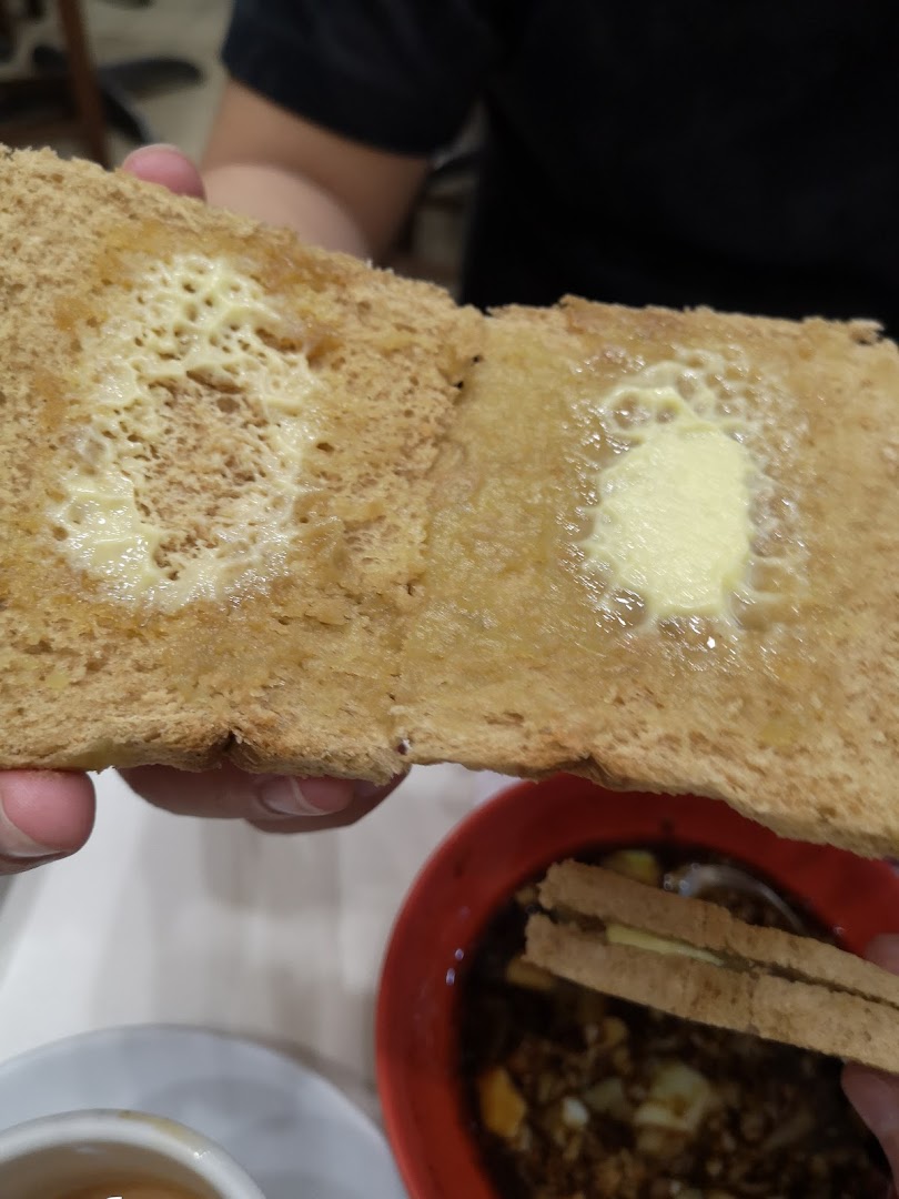 Person holding toast with butter over a bowl of soft-boiled eggs.