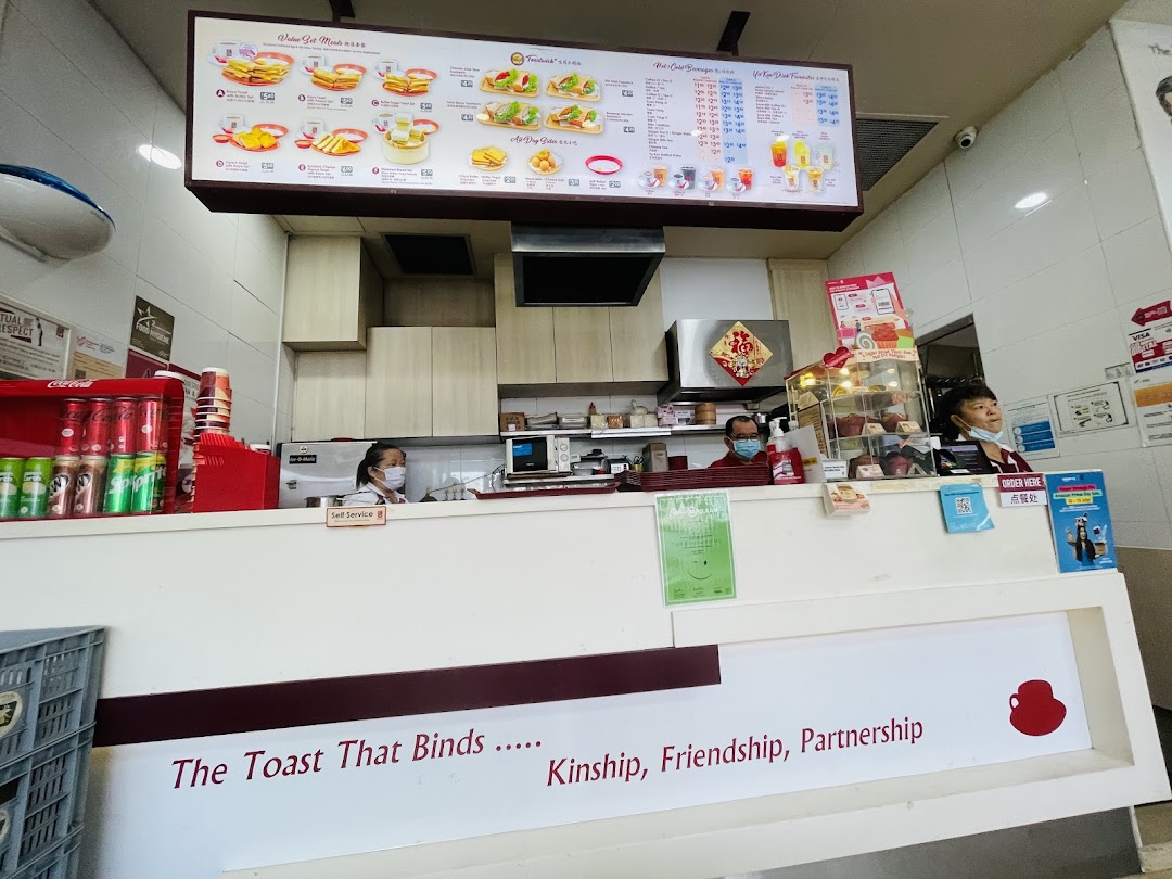 Interior view of a Ya Kun Kaya Toast shop counter with staff and menu board.