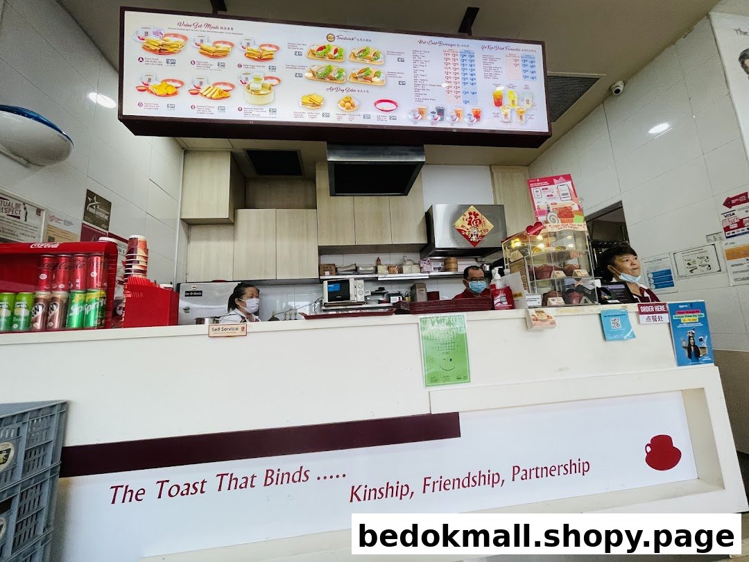 Interior view of a Ya Kun Kaya Toast shop counter with staff and menu board.