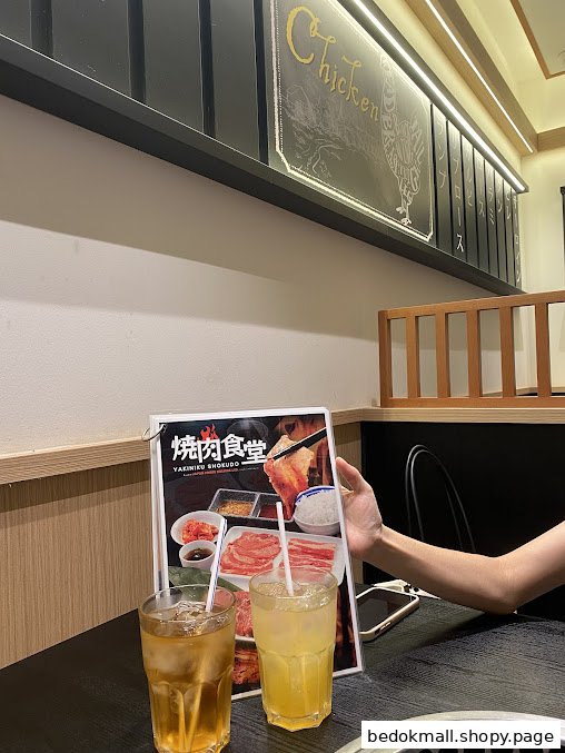 A person holds a menu at a restaurant table with two drinks.