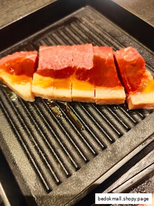 Raw meat slices with sauce on a grill pan, ready for cooking.