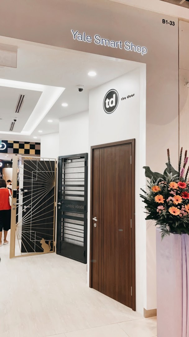 Entrance of Yale Smart Shop displaying various doors and gates with a floral arrangement.