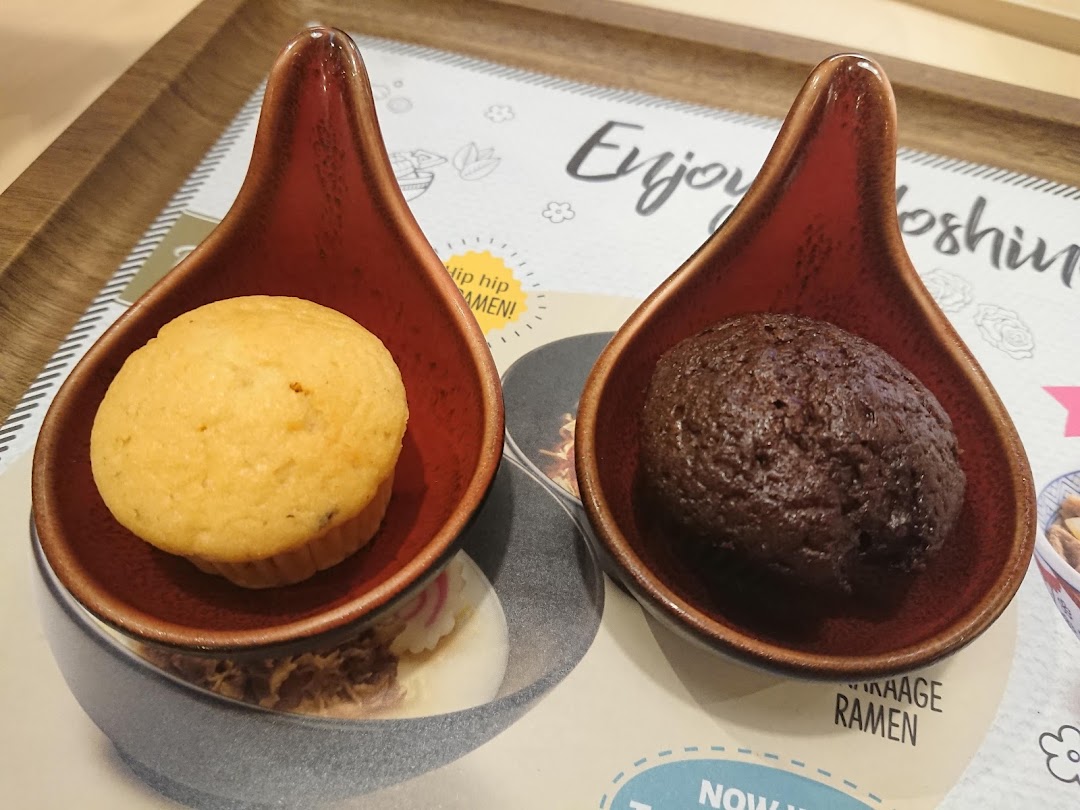 Two small muffins in ceramic dishes on a placemat.