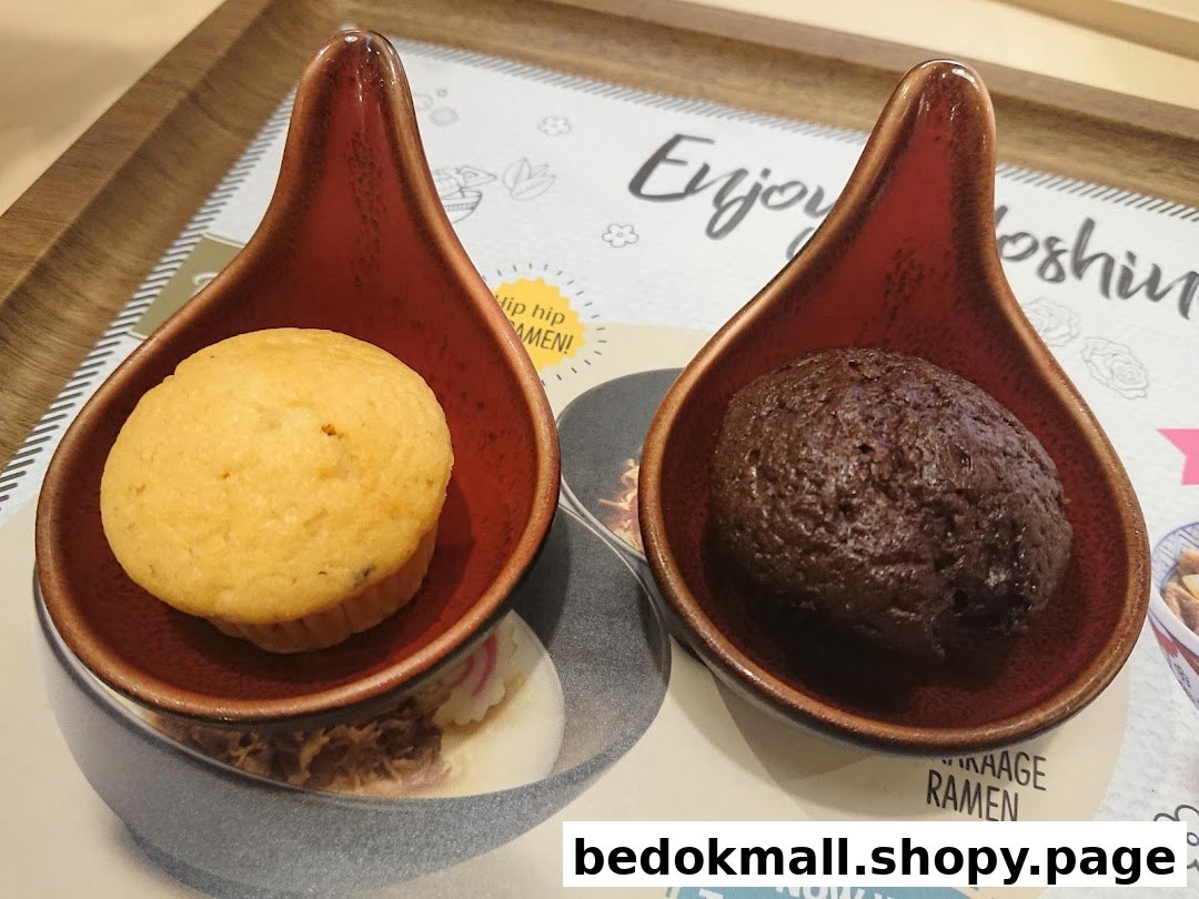 Two small muffins in ceramic dishes on a placemat.