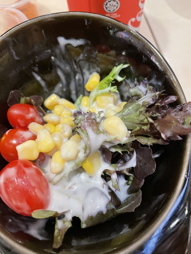 Close-up of a salad bowl with cherry tomatoes, corn, and lettuce with dressing.