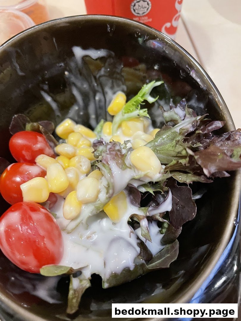 Close-up of a salad bowl with cherry tomatoes, corn, and lettuce with dressing.