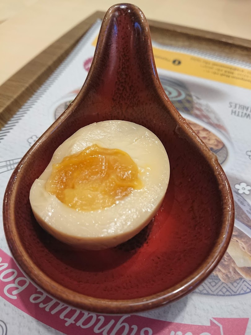 A half-cut egg with a soft yolk served in a small red dish.