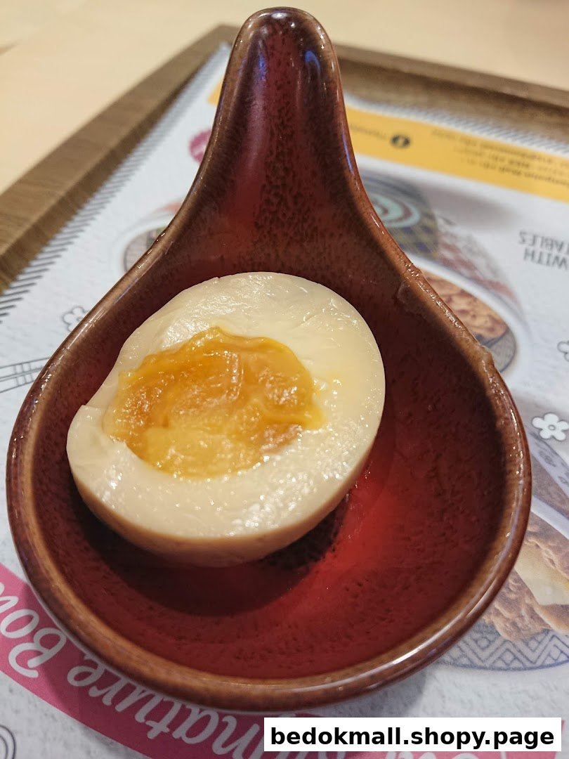 A half-cut egg with a soft yolk served in a small red dish.