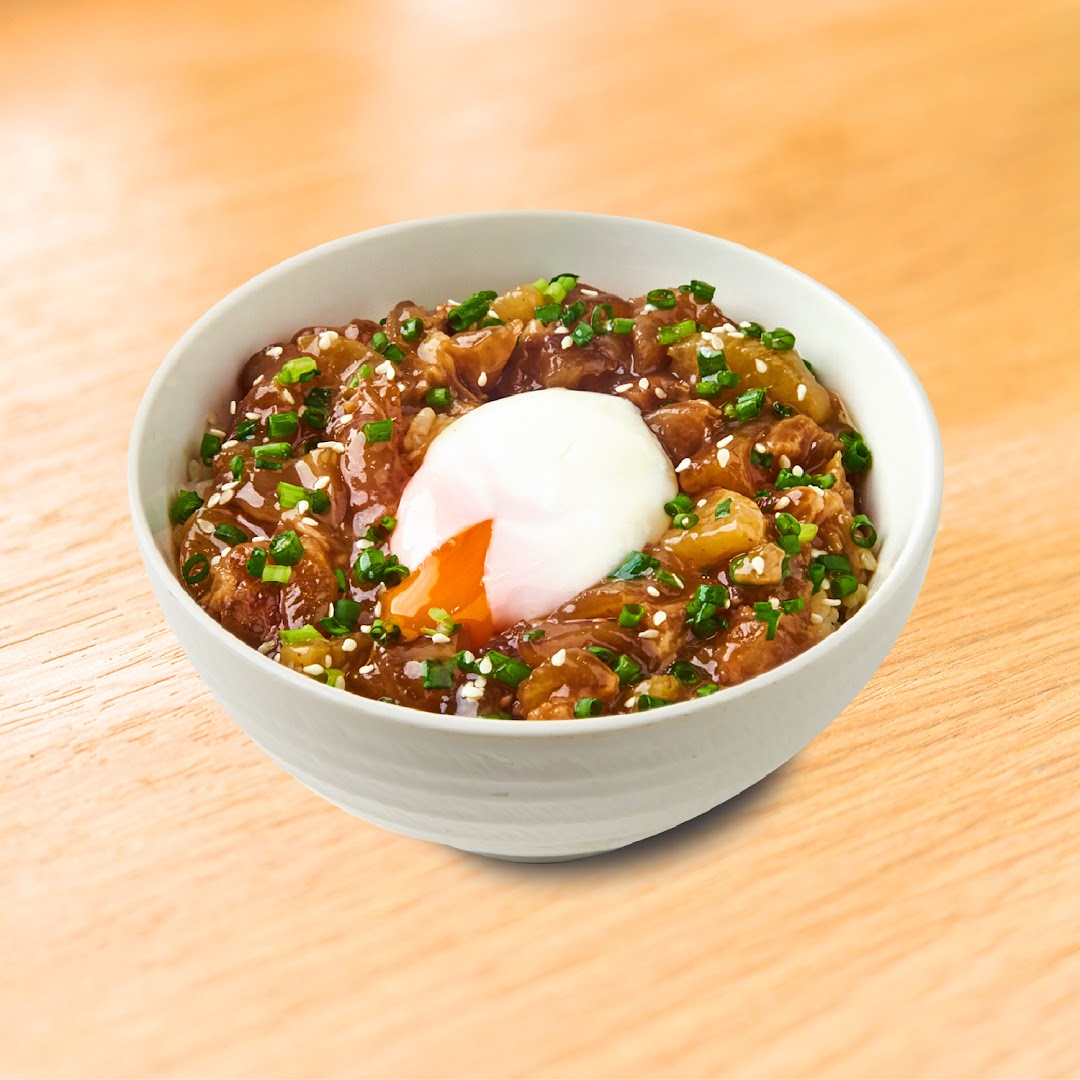 A bowl of beef and onion rice with a poached egg and green onions.
