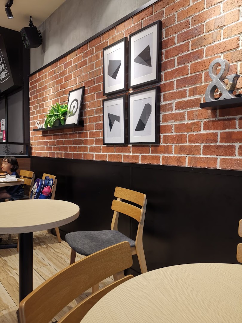 Interior view of a restaurant with brick wall, tables, chairs, and wall decor.