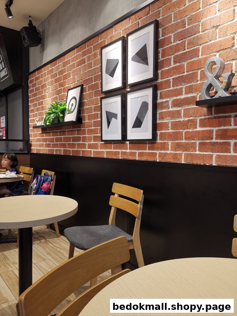 Interior view of a restaurant with brick wall, tables, chairs, and wall decor.