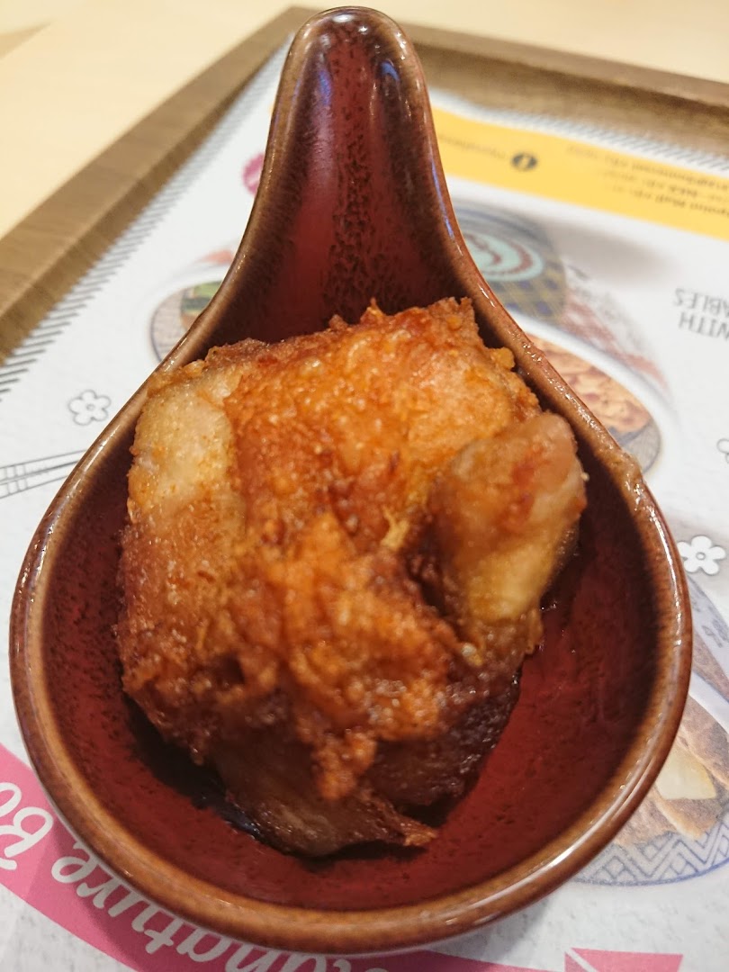 A close-up of a fried food item in a small brown dish.