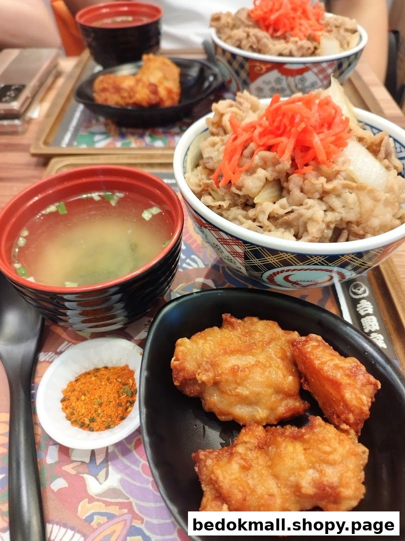 Multiple beef bowls, fried chicken, and miso soup on a table.