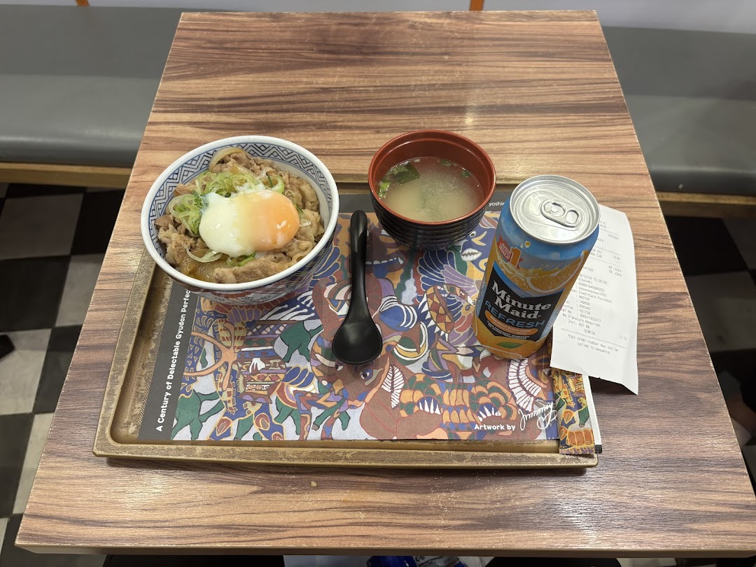 A meal with gyudon, soup, and a drink on a wooden table.