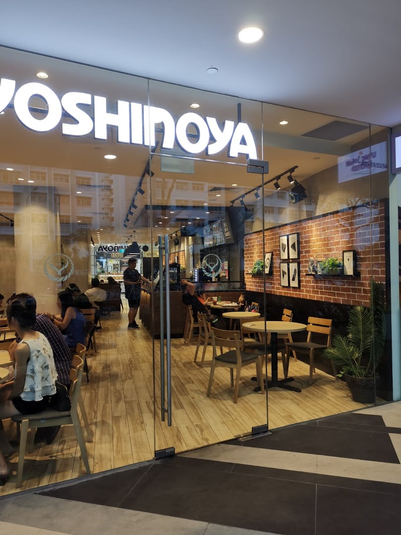 Glass entrance of Yoshinoya restaurant with customers seated inside.
