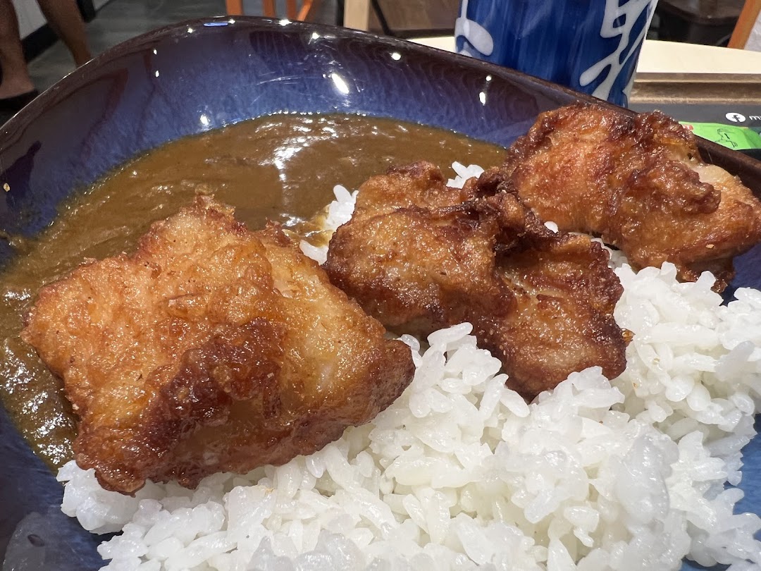 A bowl of rice with fried cutlets and curry sauce.