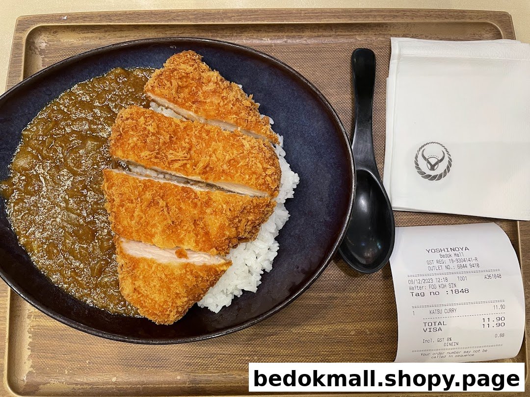 Katsu curry and rice on a tray with a spoon, napkin, and receipt.