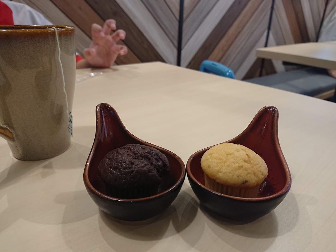 Two small muffins and a mug on a table in a shop interior.