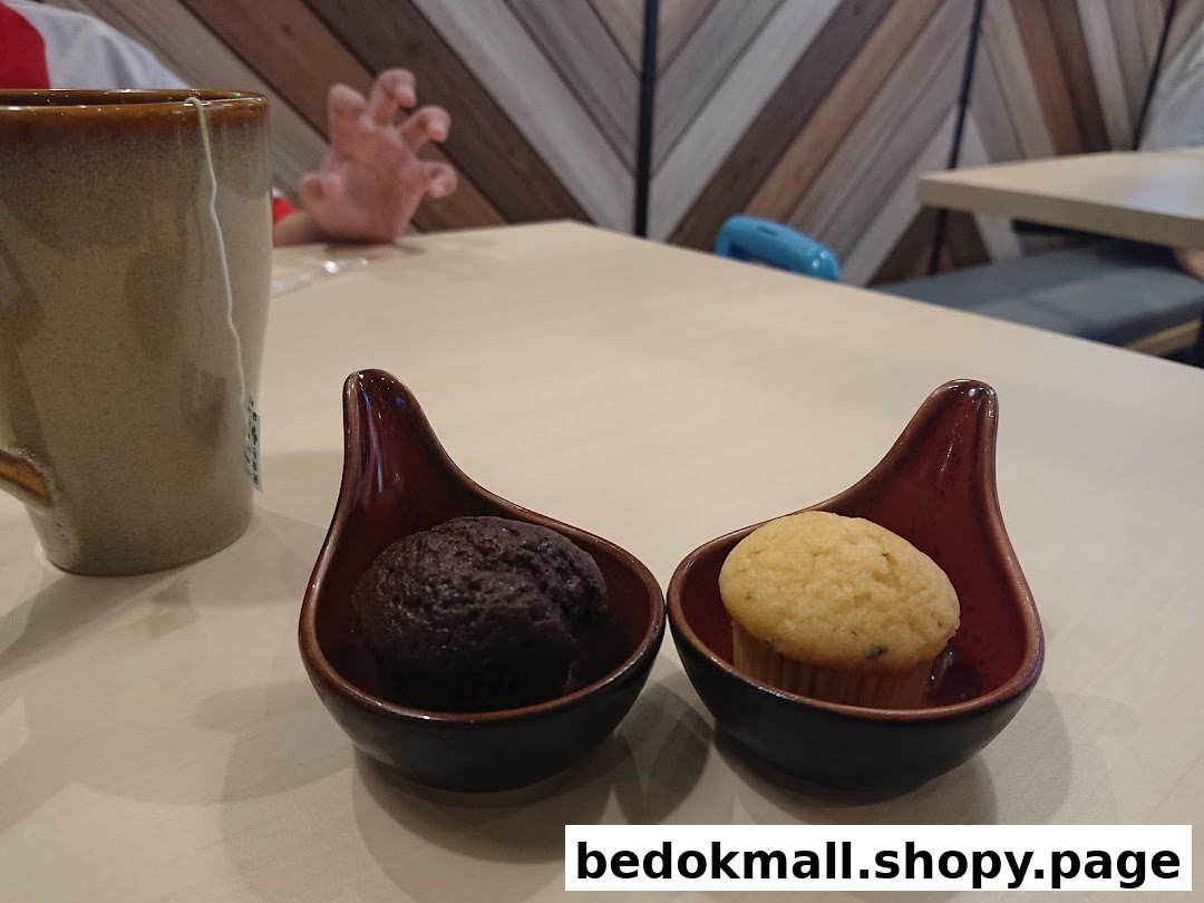 Two small muffins and a mug on a table in a shop interior.