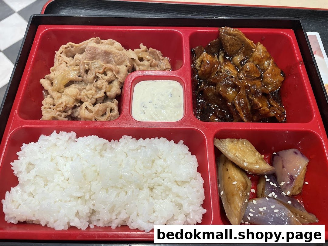 A red bento box filled with rice, beef, and vegetables.