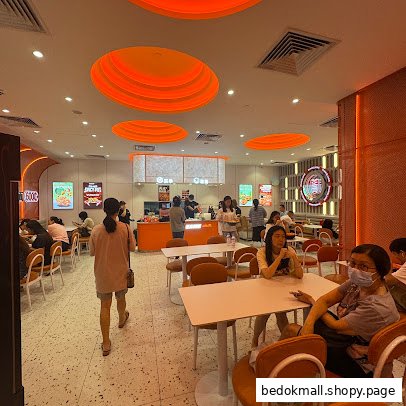 Interior view of a busy restaurant with customers dining and staff at a counter.