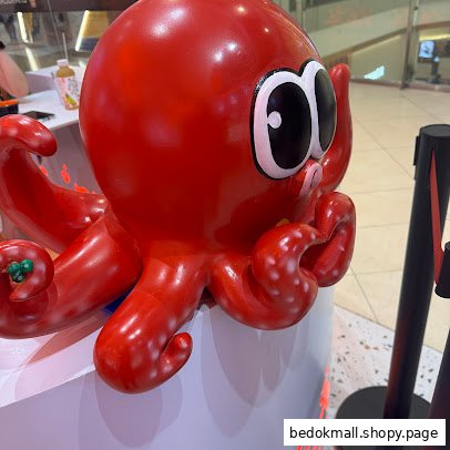 A large red octopus mascot statue with big eyes inside a retail space.