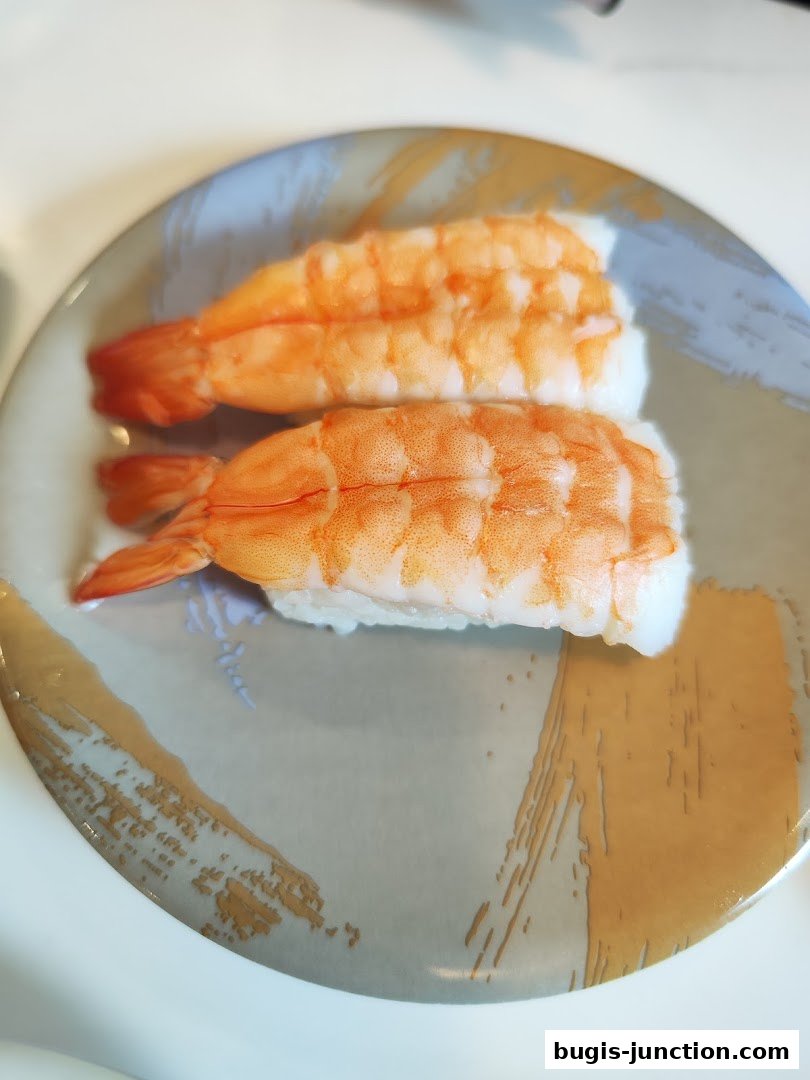Two pieces of shrimp sushi served on a decorative plate.