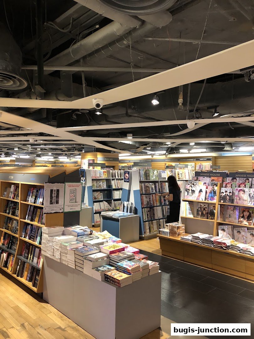 Interior view of a bookstore with shelves full of books and magazines, and a customer browsing.