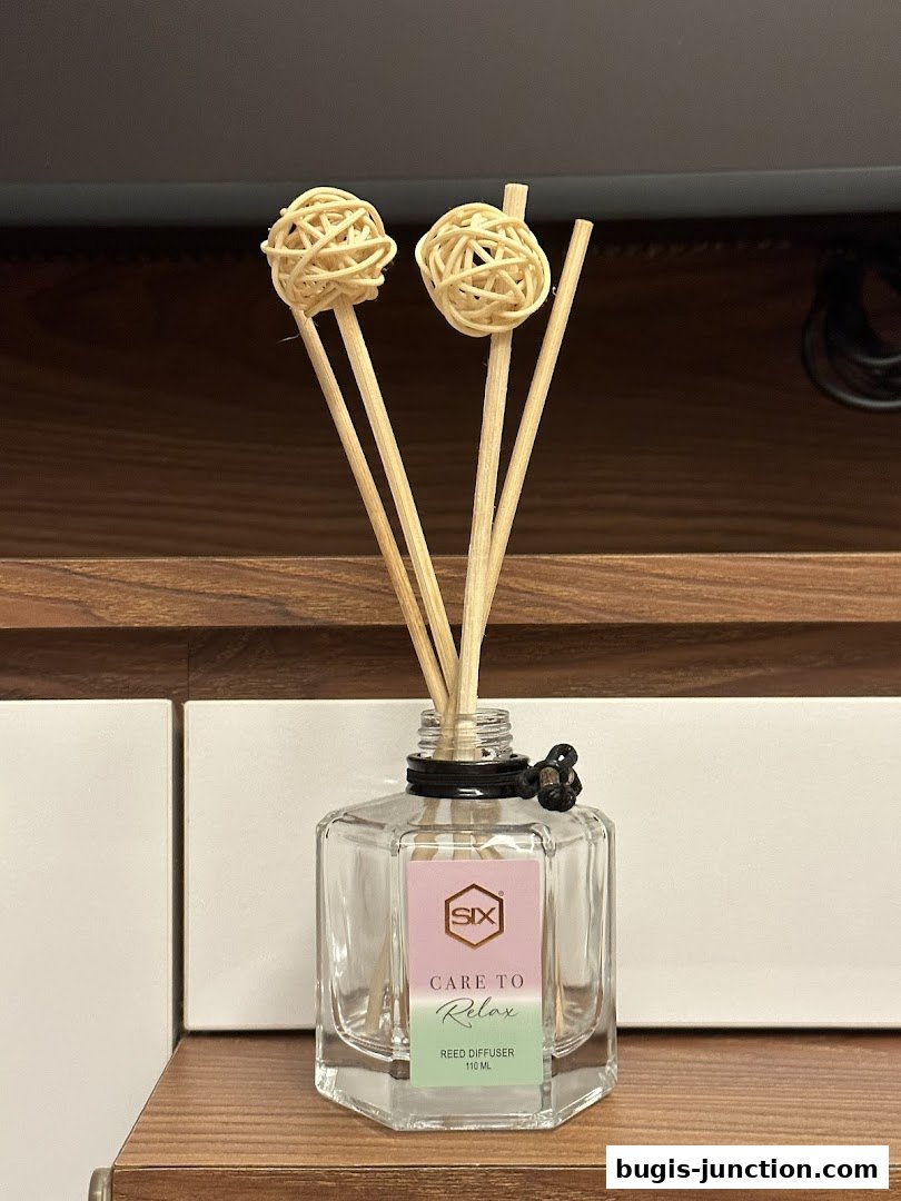A glass reed diffuser with decorative rattan balls on sticks.