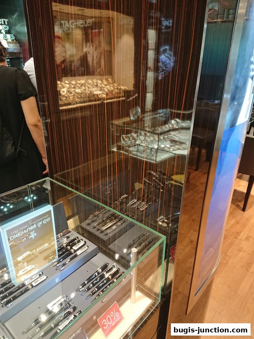 A display case filled with pens and watches, with a 30% off sign visible.
