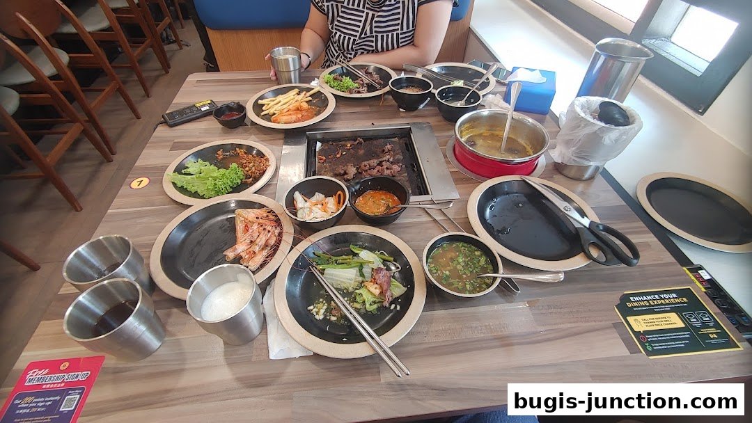 A table laden with Korean BBQ dishes, including grilled meats, seafood, and side vegetables.